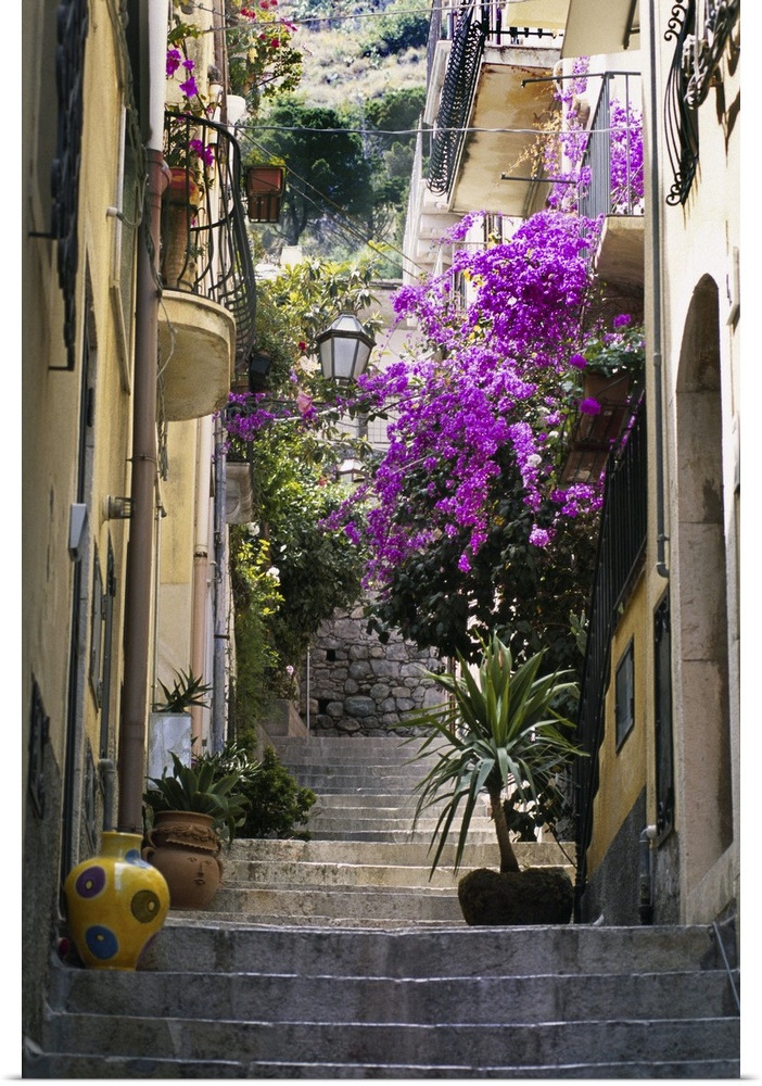 Decorations including vases and flowers line the steps of a residential alleyway in Taoramina, Italy