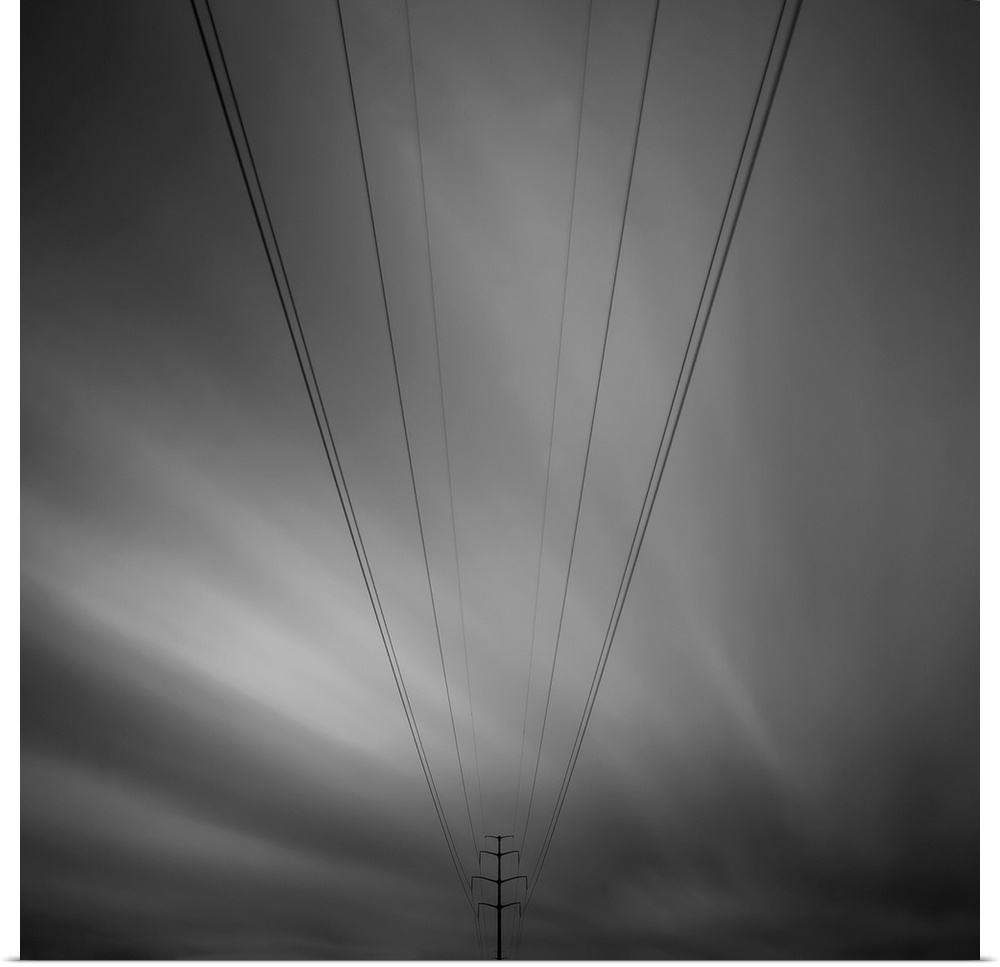 Eight electricity cables leading to a electricity pylon with a strange dramatic black and white sky behind