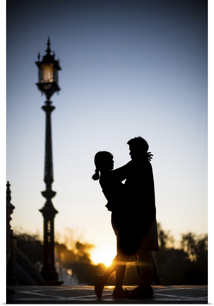 Young couple embracing at sunset, Plaza de Espana, Seville, Spain.