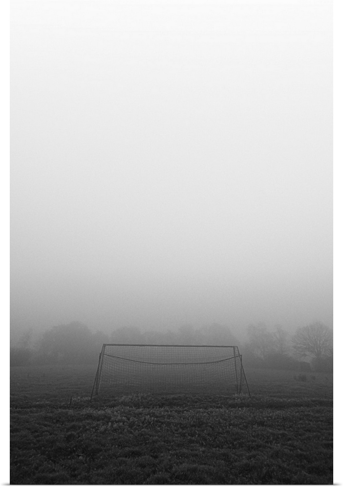 A simple football goal on an empty abandoned field on a foggy morning