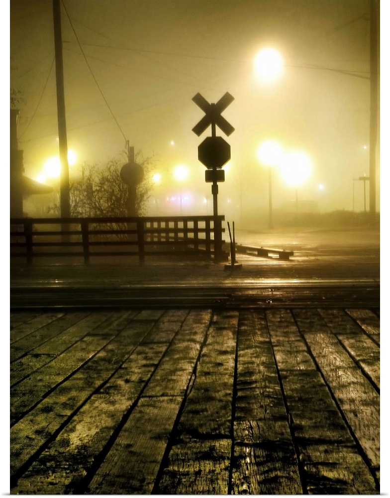 Fog at a rail crossing with street lights in the distance
