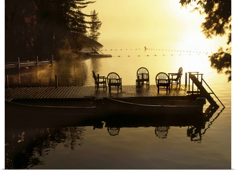 Sunsetting over a golden lake with a timber jetty with chairs