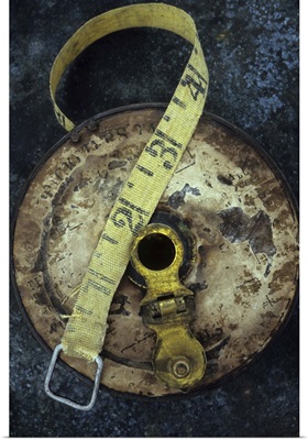 Groundsmans measuring tape in well worn metal case lying on metal sheet II