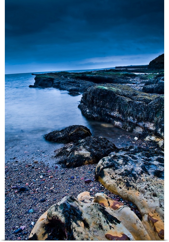 A rocky beach at dusk with storm clouds overhead
