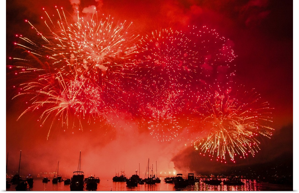 Fireworks and boats in the ocean against a red sky