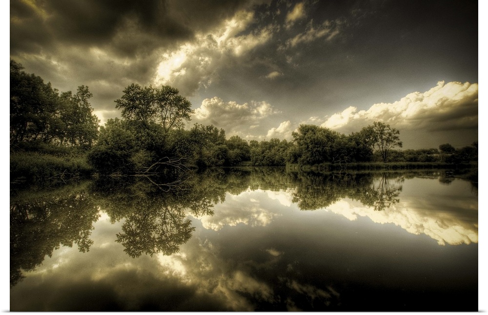 A rural  scene with trees and clouds reflected in the calm waters of a lake