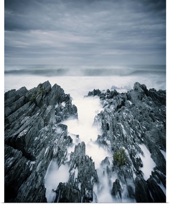 Rough sea with surf and rugged rocks under stormy sky