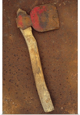 Rusty axe once red on makeshift wooden handle lying on rusty metal sheet