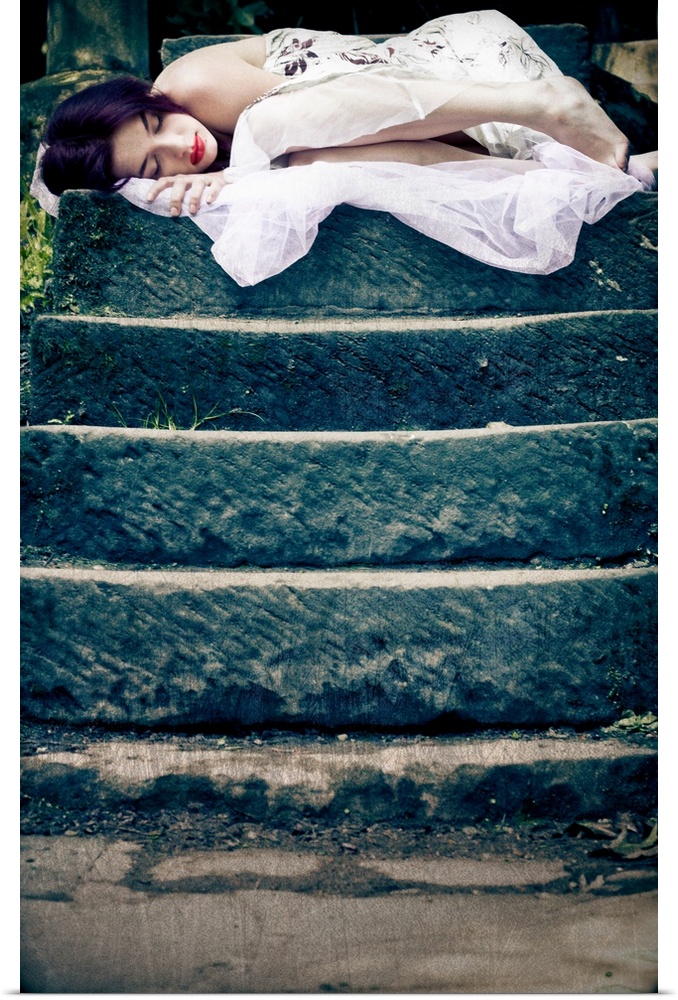 Image of a sleeping young woman on the top of a set of stone steps in a peaceful garden setting