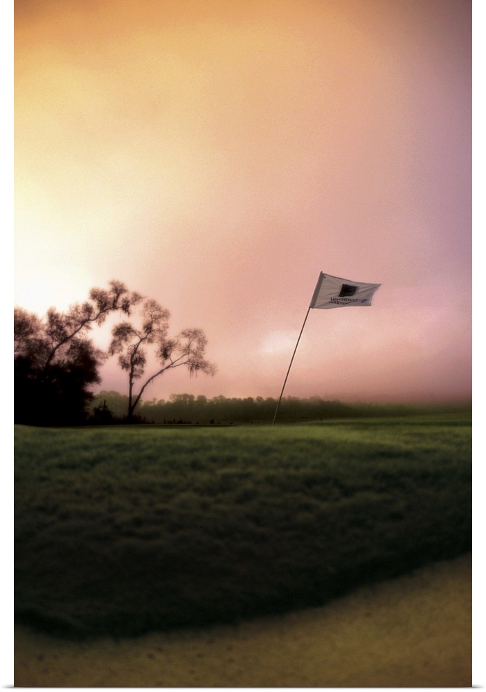 The flag pole on a golf course bends and shakes in the wind
