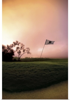 The flag pole on a golf course bends and shakes in the wind