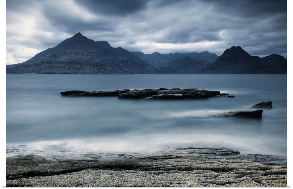 Looking across the sea to the Isle of Skye with mountains under a grey sky