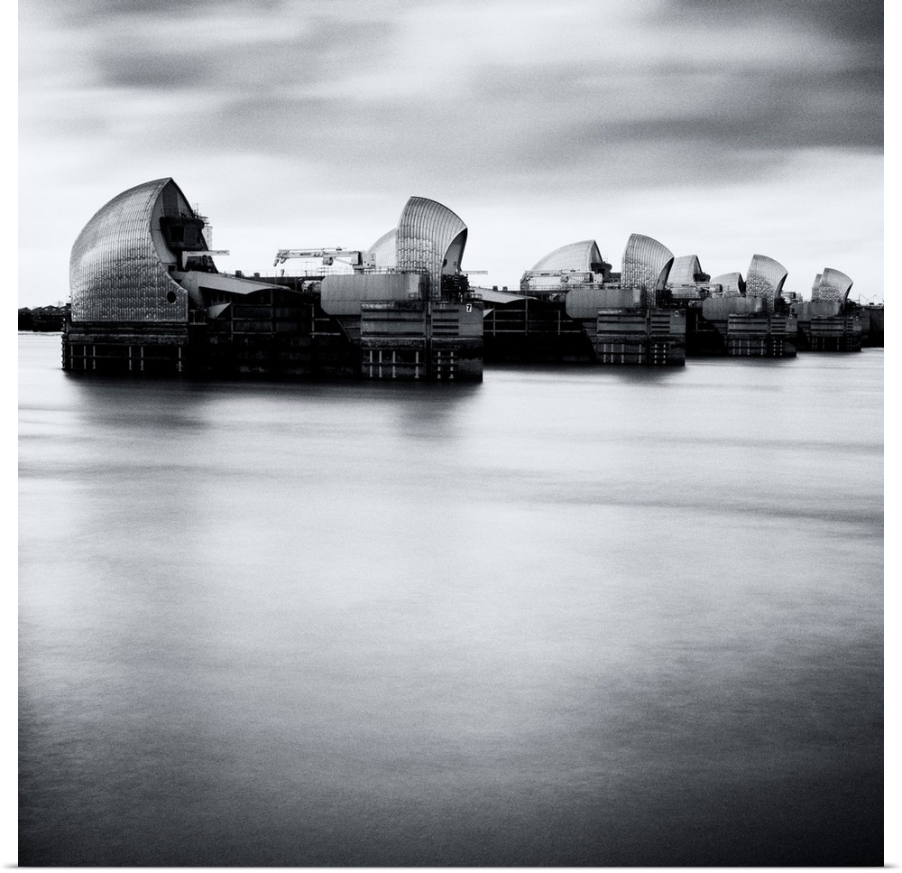 Thames Barrier, london with Canary Wharf in background under grey sky