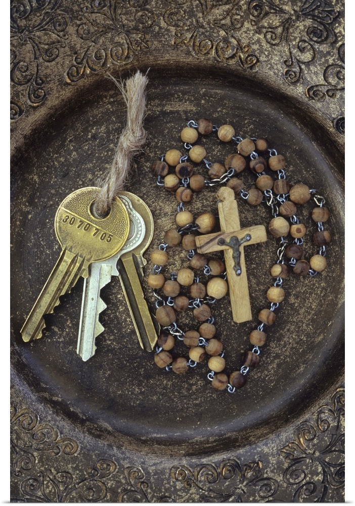Three brass doorkeys tied with string lying next to rosary with crucifix in brown and gold bowl with intricate pattern