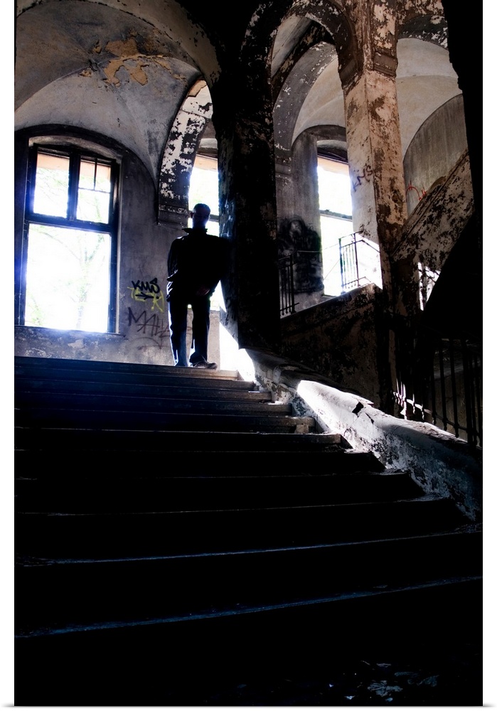 Silhouette of a man standing on some old stairs in a large building