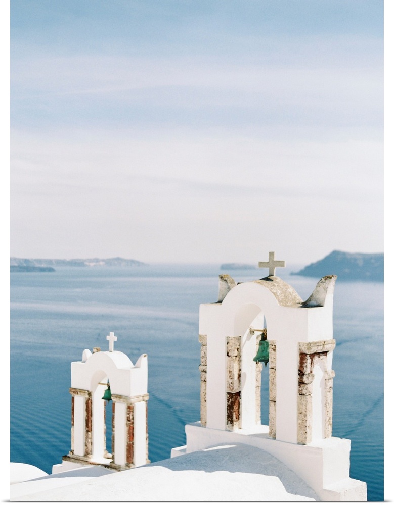 Photograph of church bell towers overlooking the ocean in the Greek city of Oia, Santorini.