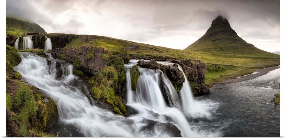 Stormy clouds gather over tranquil waterfalls in this luscious green landscape photograph.
