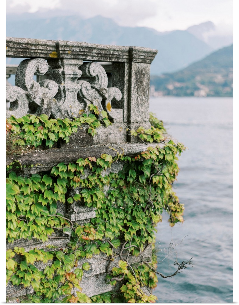 A photograph of an ornate stone balcony covered with ivy on the shore of Lake Como, Italy.