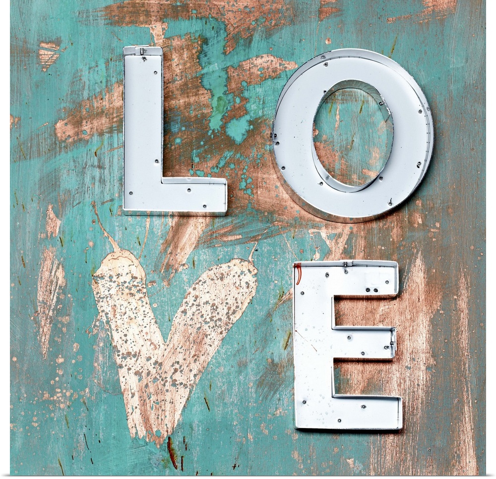 The word "Love" made of metal letters and a painted heart on weathered teal boards.