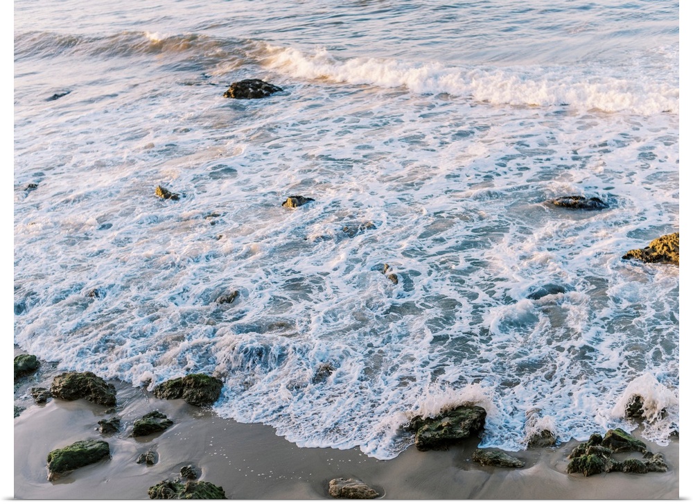 A photograph of gentle waves lapping the beach.