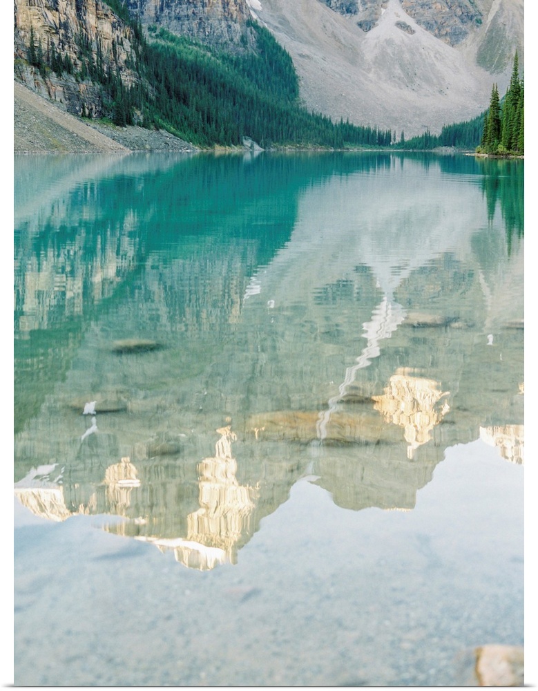 A photograph of mountains reflecting in the clear blue water of Moraine Lake, Banff National Park, Alberta, Canada.