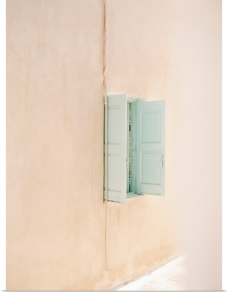 Photograph of a small window with pale blue shutters in a peach colored wall.