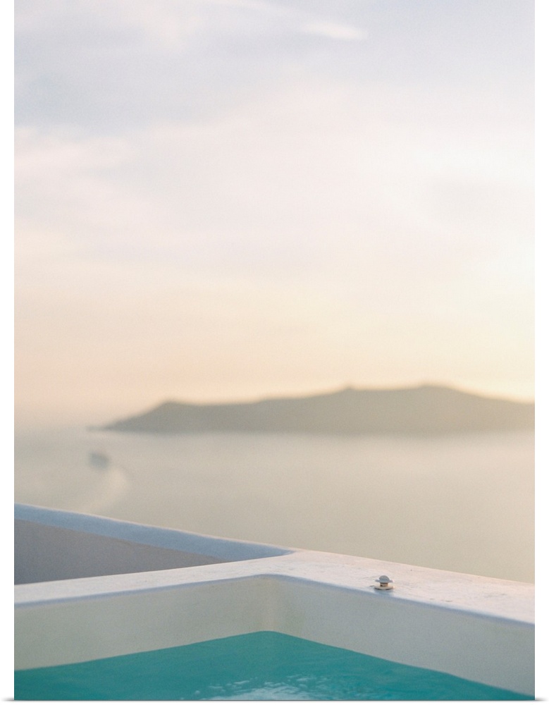 Photograph of the edge of a swimming pool with an island in the distance, Santorini, Greece.