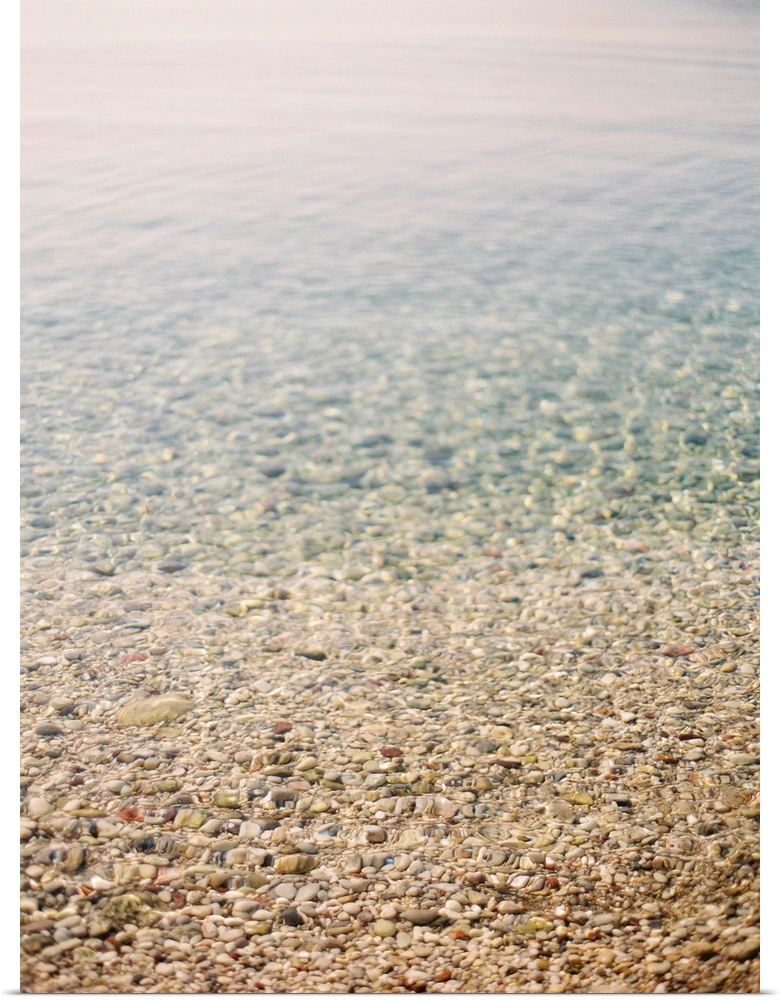 Photograph of shallow ocean water on a pebble beach, Corfu, Greece.