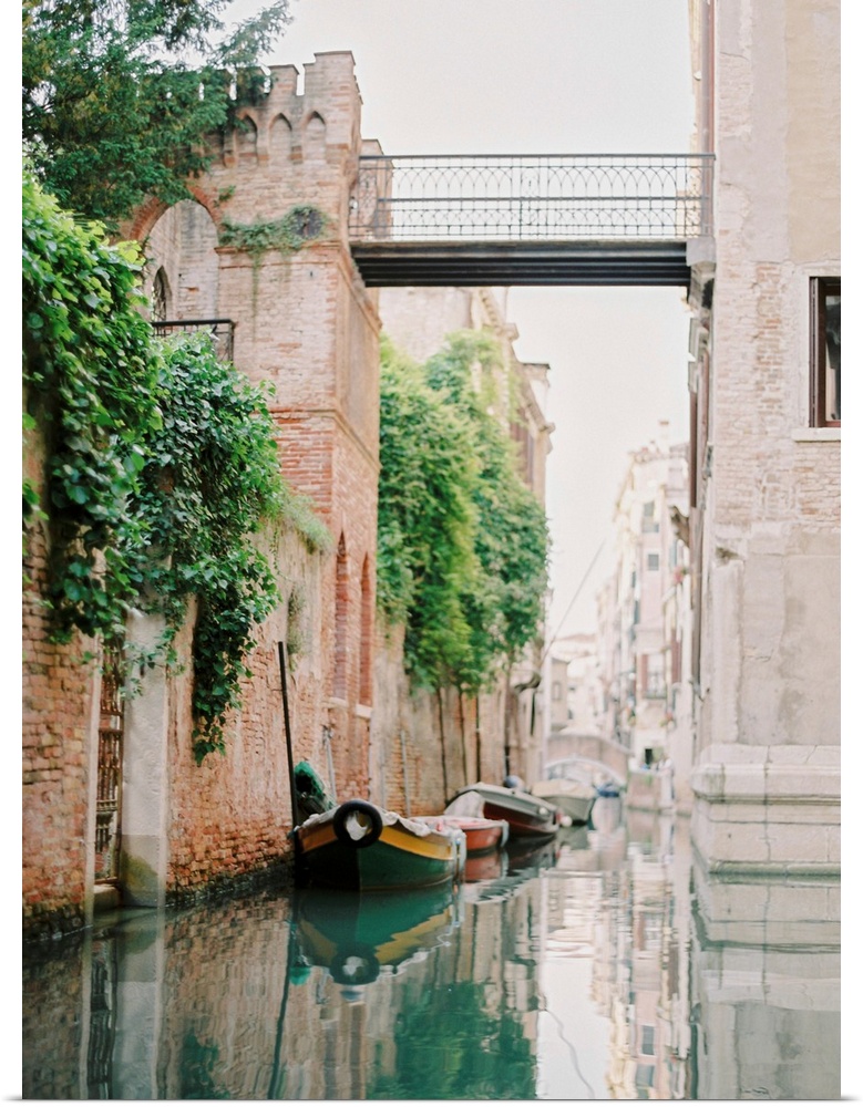 Photograph of small boats moored beneath an old brick wall, Venice, Italy.
