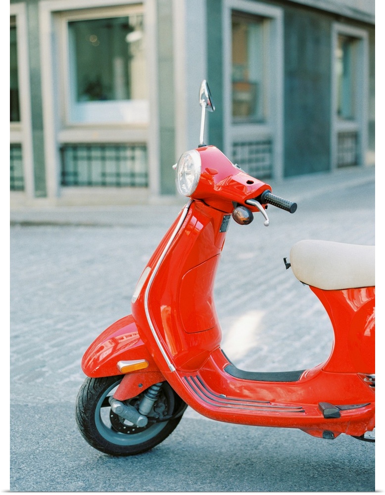 A photograph of a red scooter parked on the street.