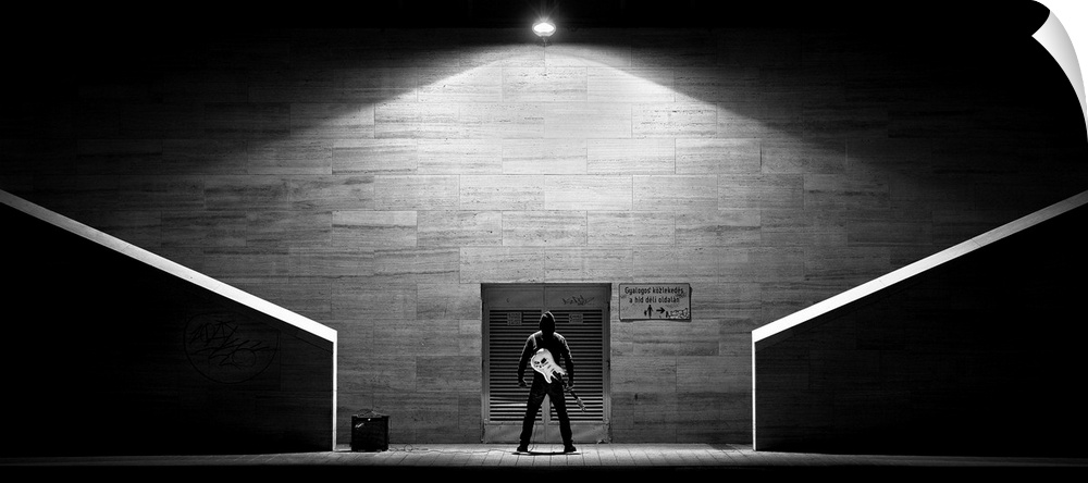 A man holding a guitar standing outside a concert hall door ready to enter.