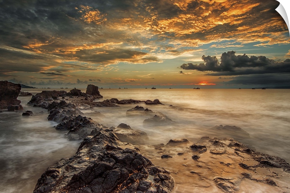 A beach scene under a sky filled with dramatic clouds of sunset.