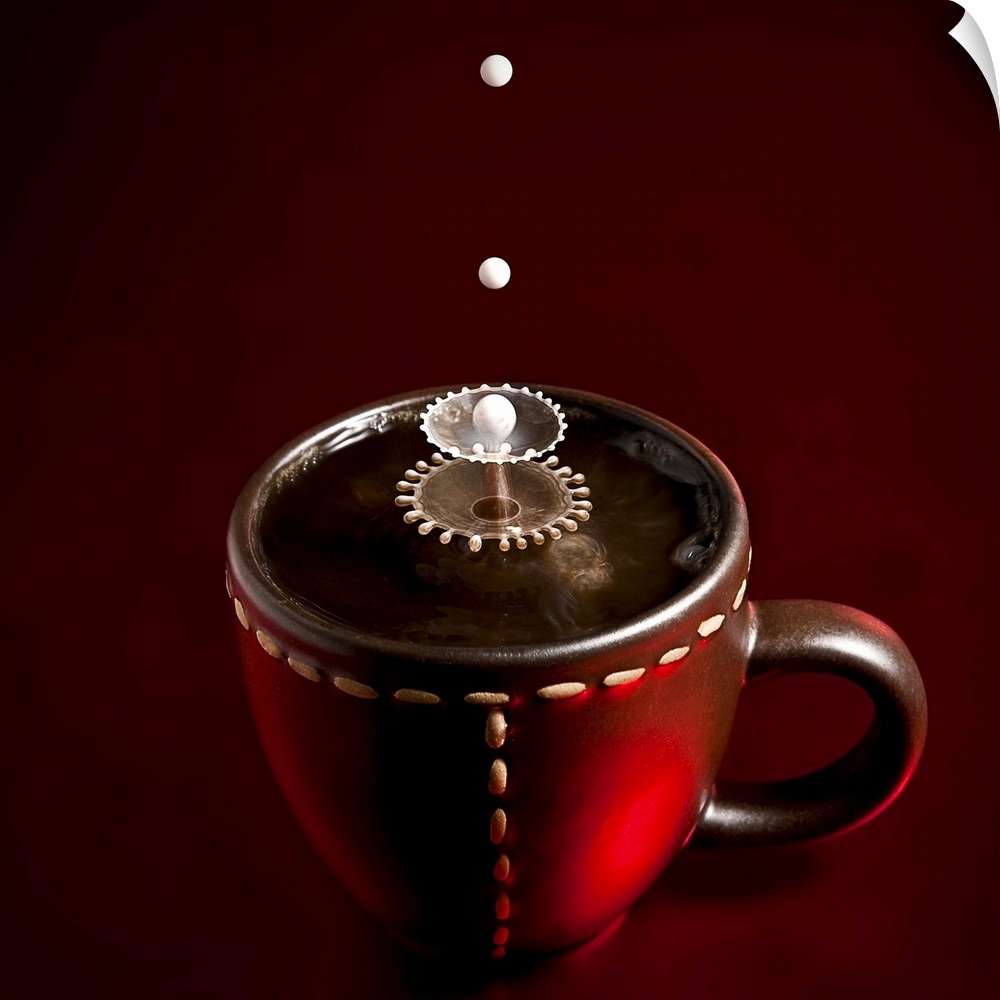Conceptual image of droplets of milk splashing into coffee in a mug, creating abstract patterns.