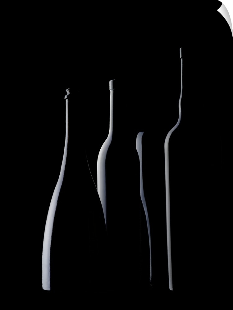 Four glass bottles of different shapes with light on one side.