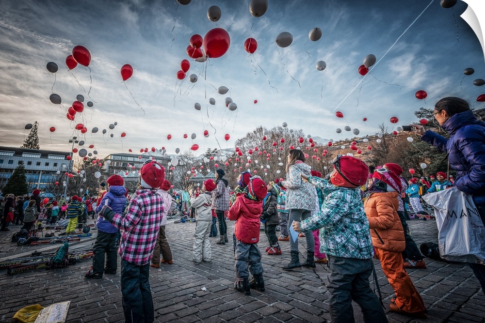 Crowd of people releasing silver and red balloons into the air to celebrate the new year.