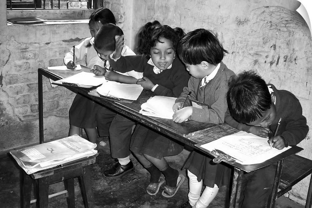 A group of young schoolchildren in Nepal help each other work on their writing.