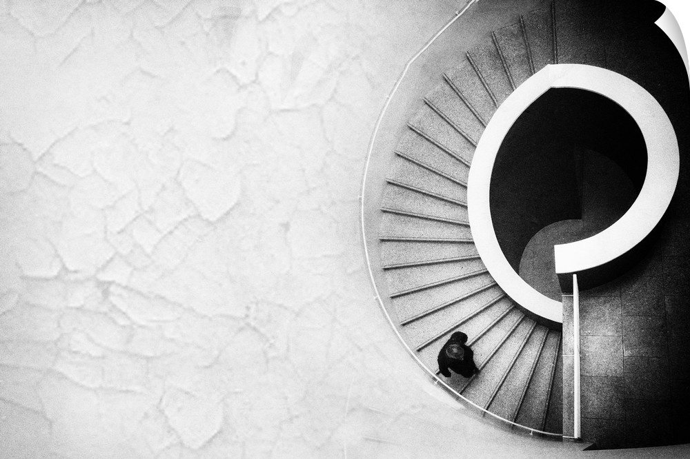 Aerial view of a curved staircase with a person walking down.