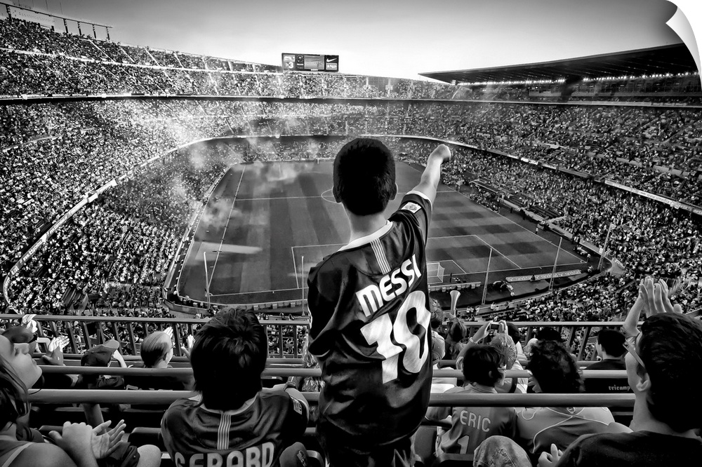 A black and white photograph of a child standing up among thousands of seated people in a sports stadium.