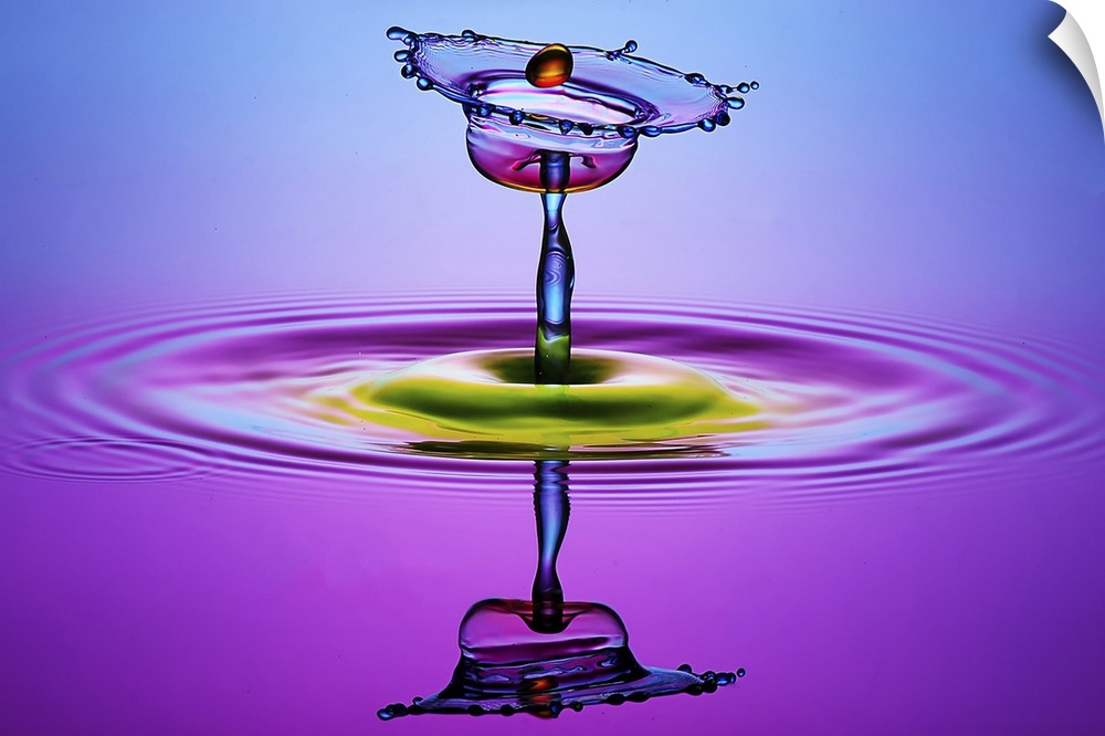 A macro photograph of a tiny water splash caught in mid air and illuminated in vibrant colors.