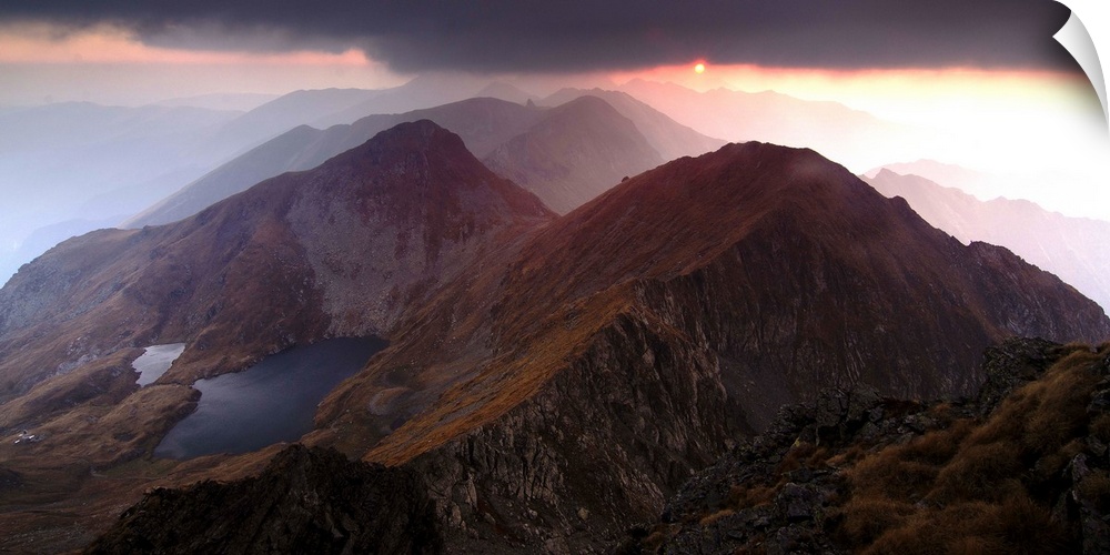 Sunset just visible under dark clouds over the Fagaras Mountains in Romania.