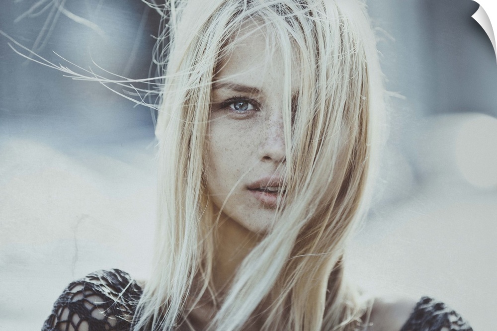 Portrait of a blond woman with her hair blowing in the wind, obscuring her face.