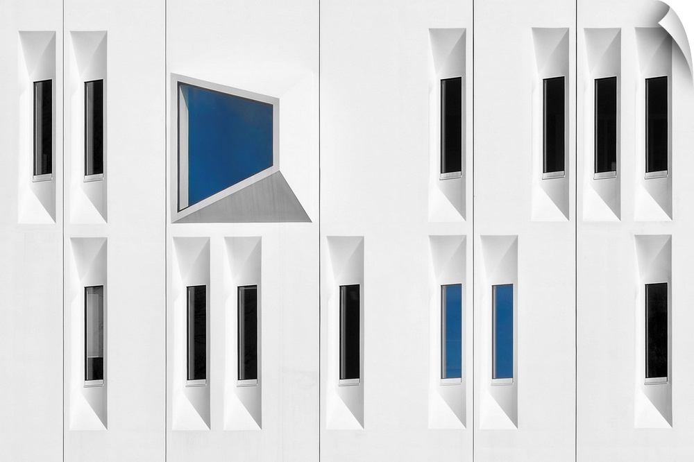 Facade of a white building with narrow windows reflecting black and blue.