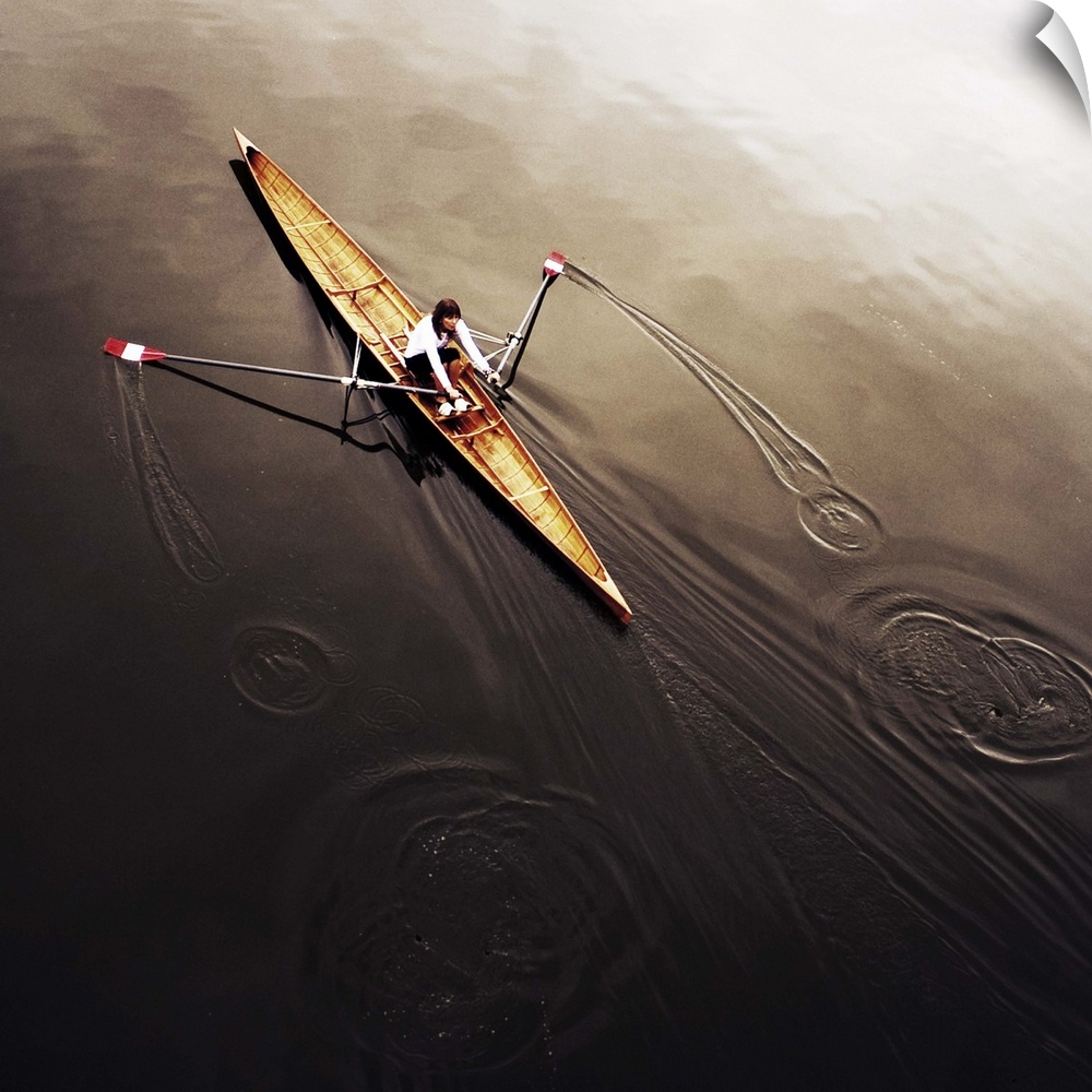 A female athlete rowing on still, dark water, leaving a small wake.