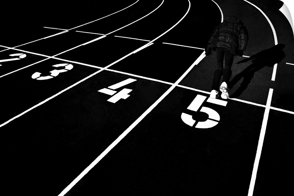 A man running in the number 5 lane on a track in a stadium, in high contrast black and white.