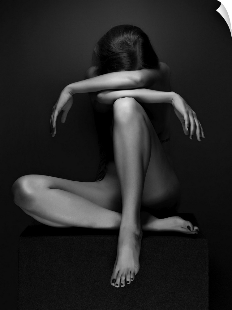 Black and white fine art photograph of a woman sitting down, creating angles with her body, resembling a sculpture.
