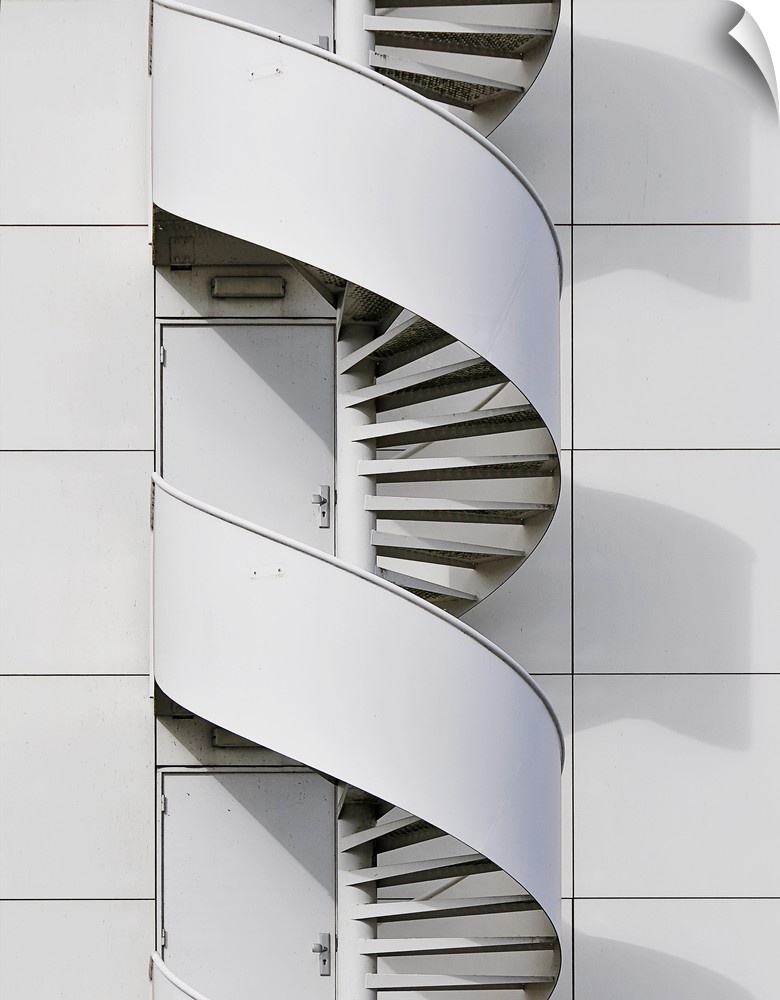 Geometric photograph of a swirly fire escape running along the side of a white building.
