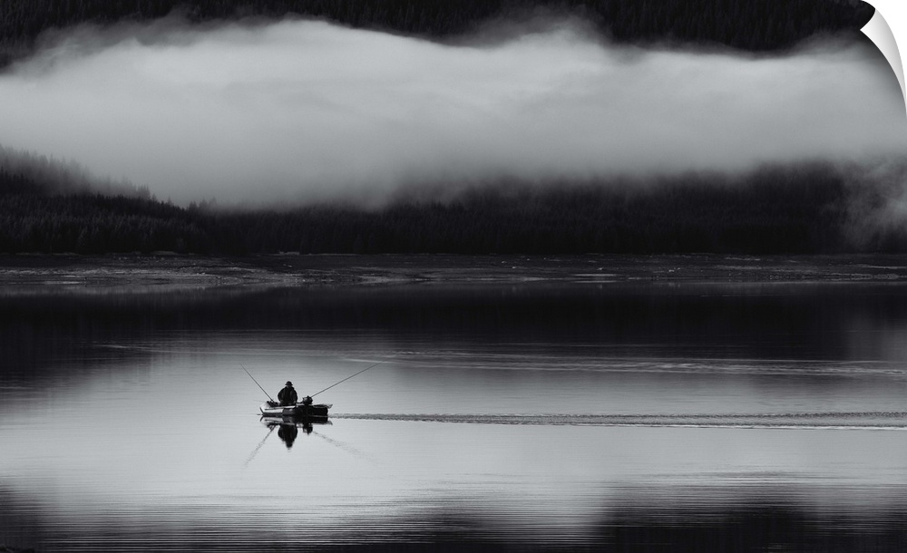 Fishing on a lake with a thick cloud of fog hovering over a forest.