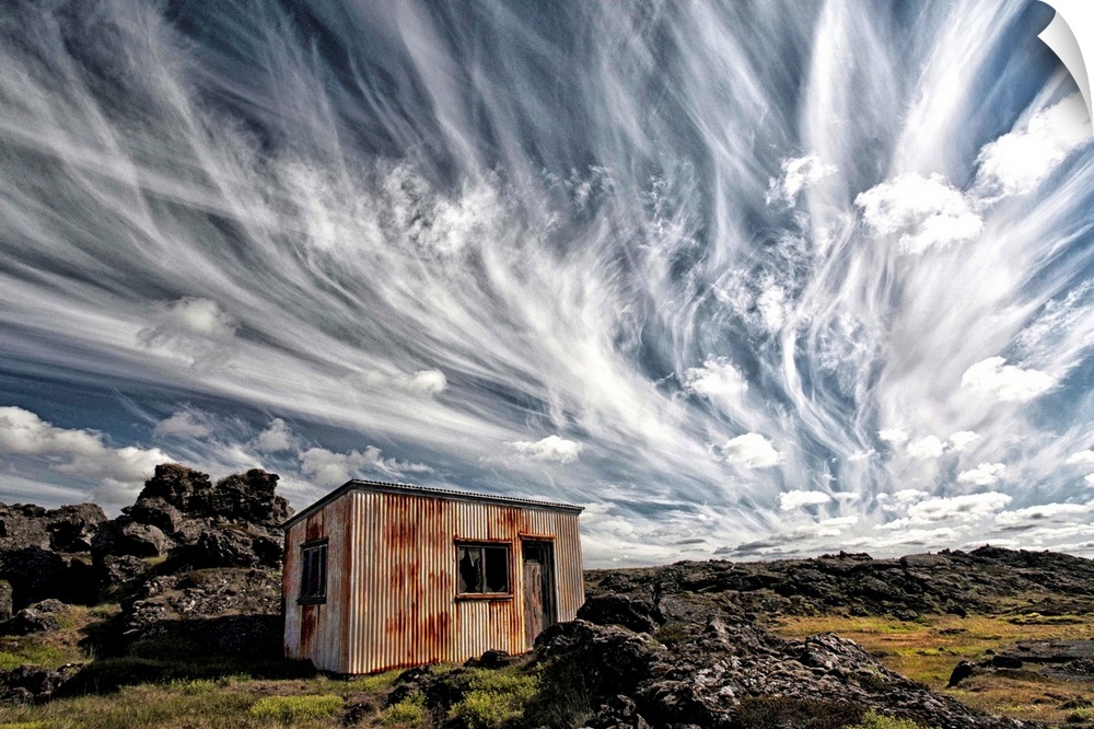 A dramatic skyscape over a derelict shack in the Icelandic countryside.