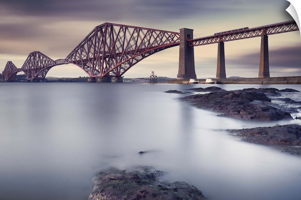View from the rocky shore of the criss-crossing beams of a bridge in Edinburgh, Scotland.