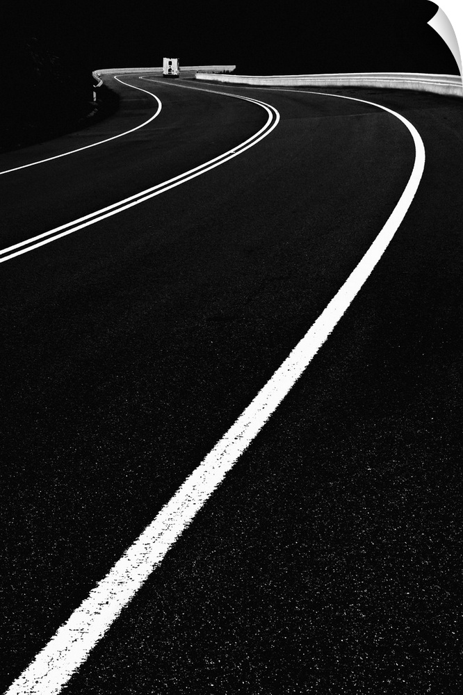 High contrast black and white image of lines on a road curving around a bend.